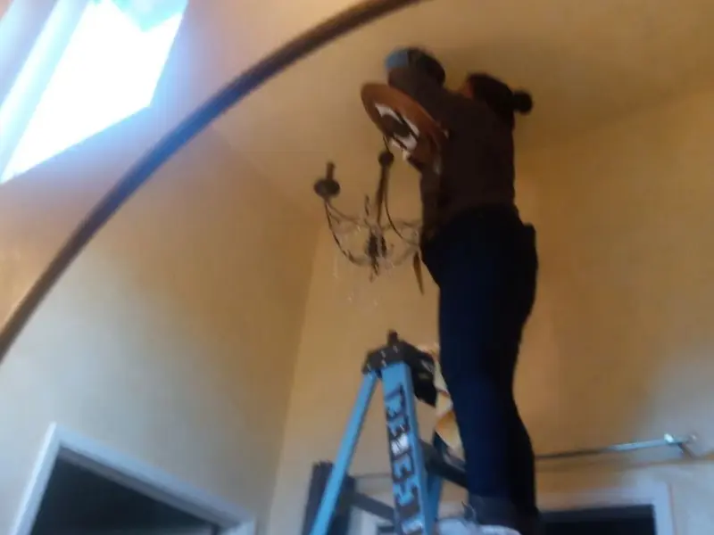 Electrician installing a chandelier in a Rexburg residence